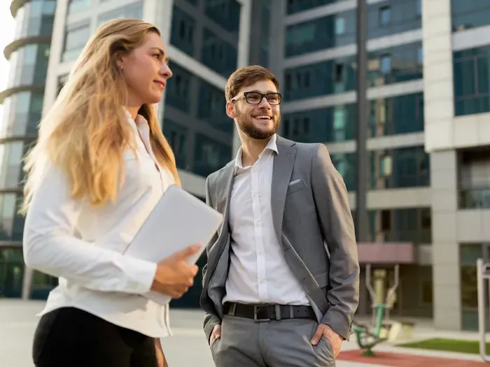 Smiling business professionals standing outside modern office complex, discussing plans and local services